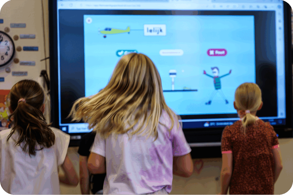 Drie meiden bewegen fanatiek om antwoord te geven op de Fit & Vaardig vraag die op het digibord staat.